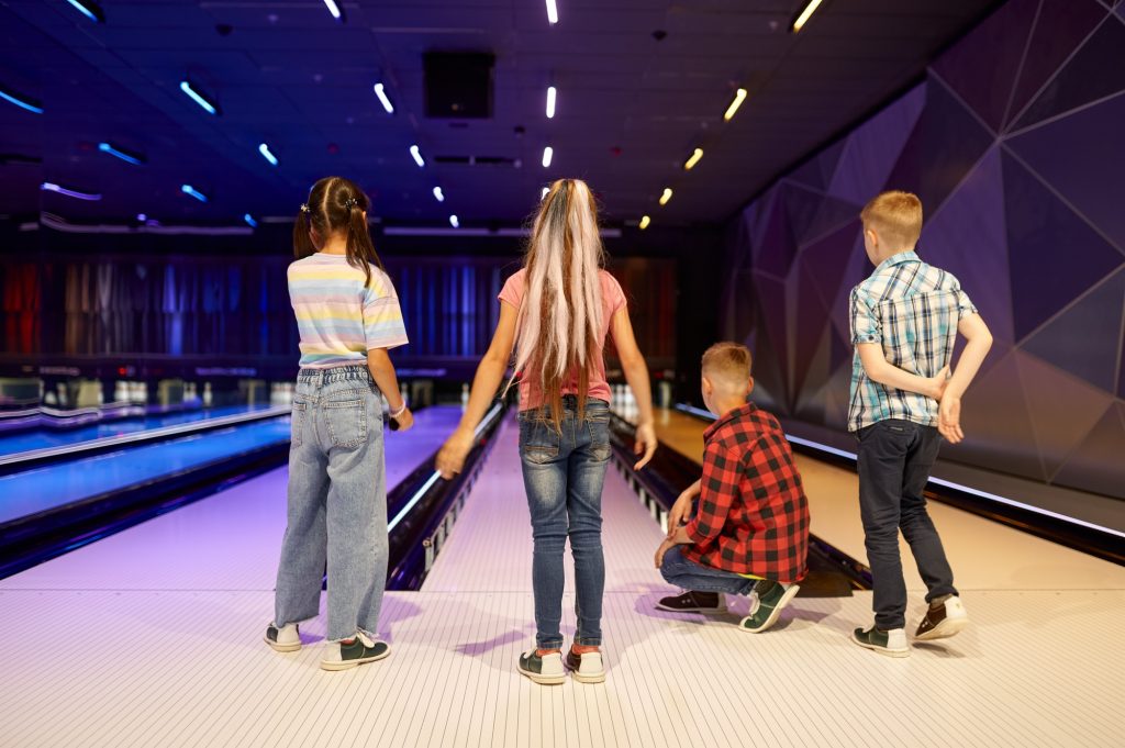 Children throw a ball on the lane in bowling alley
