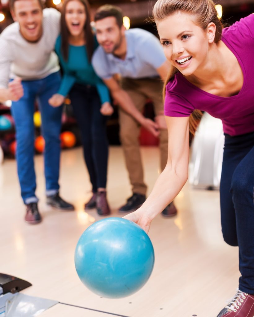 Come on! Beautiful young women throwing a bowling ball while three people cheering